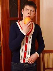 Sexy boy plays with an orange while stripping off